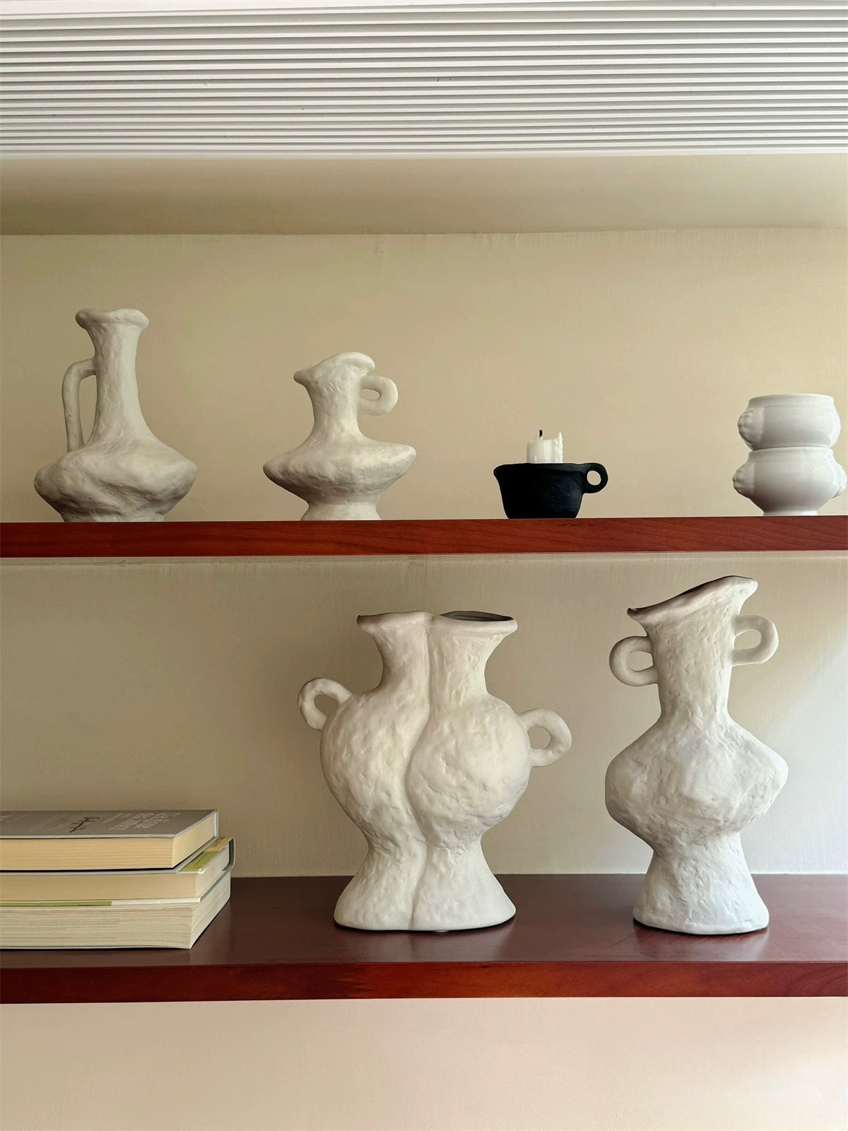 White ceramic vases on wooden shelves against a beige wall.