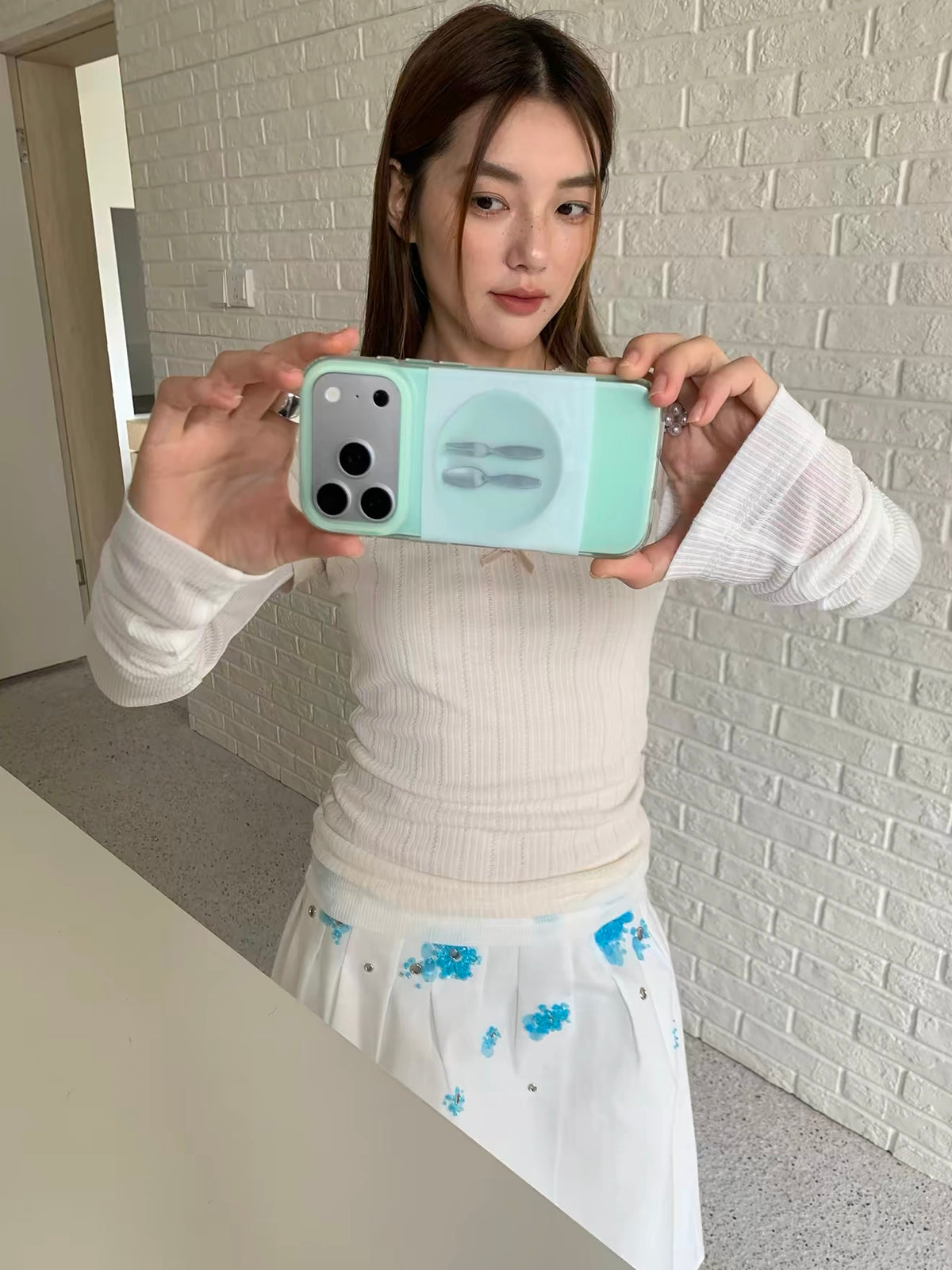 A mint cutlery phone case held horizontally for a mirror selfie, with the circular plate design centered.