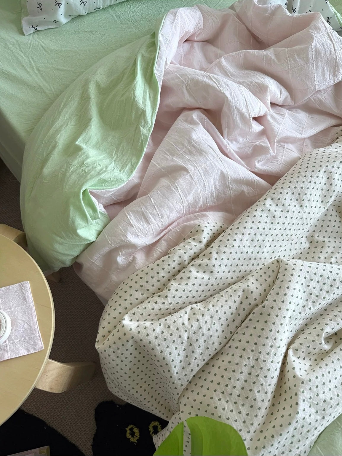 Close-up of mint green and pale pink cotton patchwork bedding with small dotted print