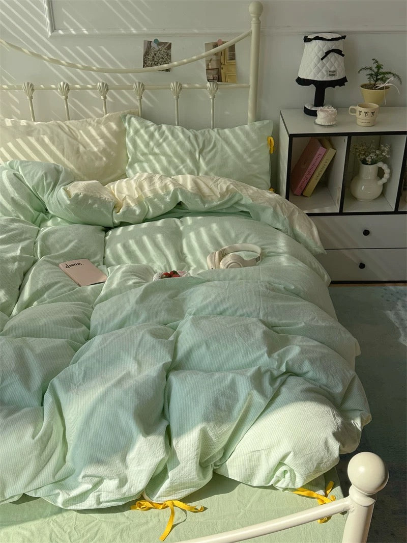 Light green bedding set on a bed with a white headboard and shelves in the background.