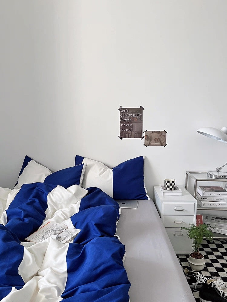 Bedroom with blue and white bedding, nightstands, and decorative items on a checkered floor.