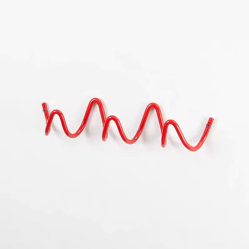 Wavy black metal wall hook rack for coats, bags and hats, modern minimalist entryway decor.