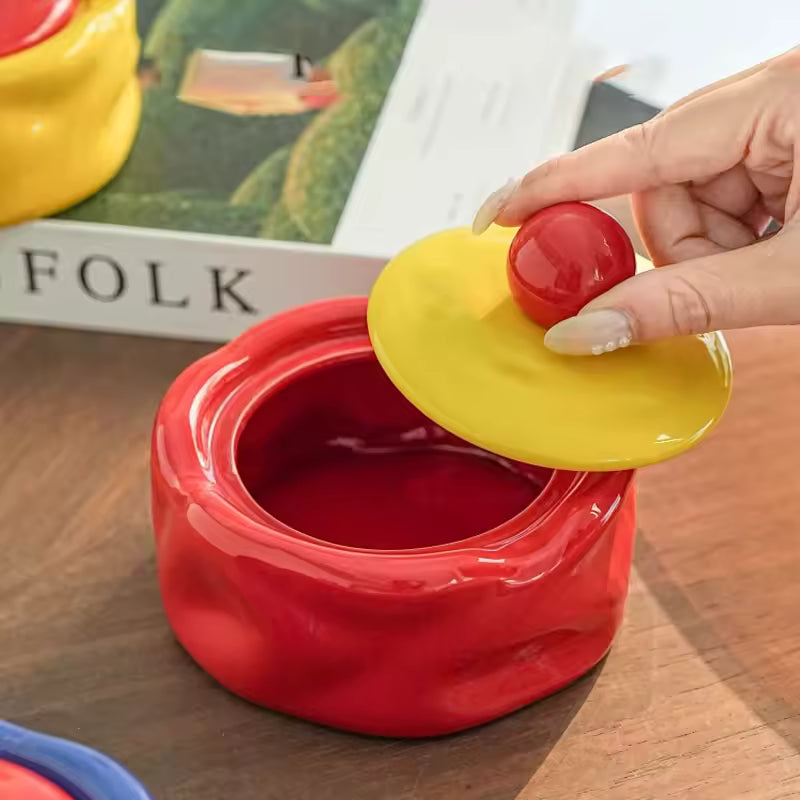 Red container with a yellow lid being opened by a hand on a wooden surface.