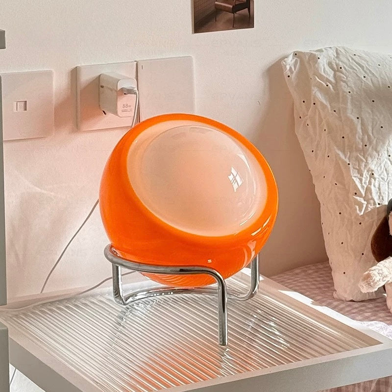 Orange spherical lamp on a stand in a room setting