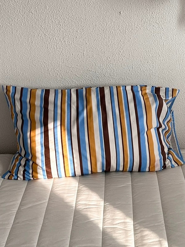 A multicolor striped pillow case with blue, yellow and brown bands separated by light stripes.
