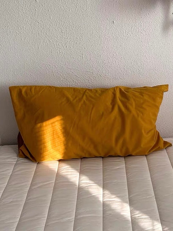 A mustard pillowcase in solid yellow with visible fabric creases.