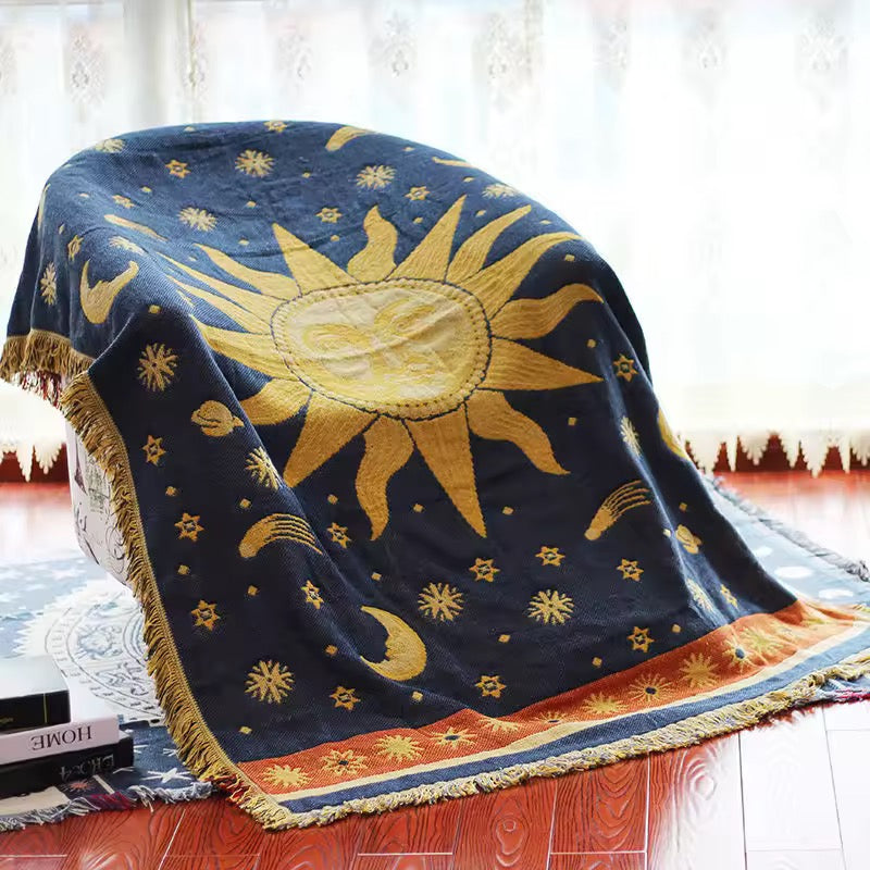 Decorative blanket with sun and star pattern on a wooden floor