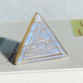 Blue flash moonstone crystal pyramid with evil eye carving, perfect for yoga, meditation, and home decor. Natural crystal healing properties.