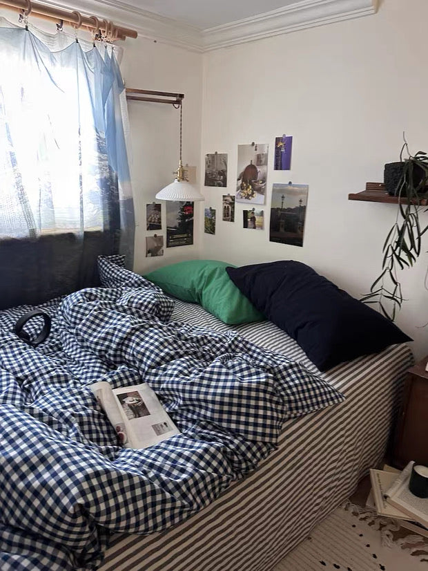 Bedroom with a bed covered in checkered sheets, pillows, and a nightstand.