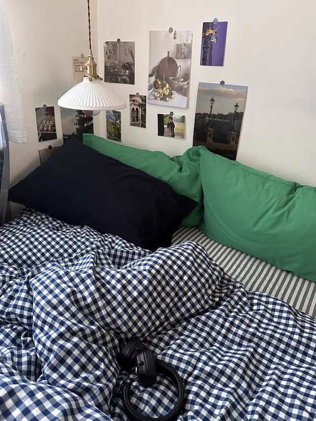 Blue gingham cotton duvet cover styled with green pillows in cozy preppy bedroom decor.