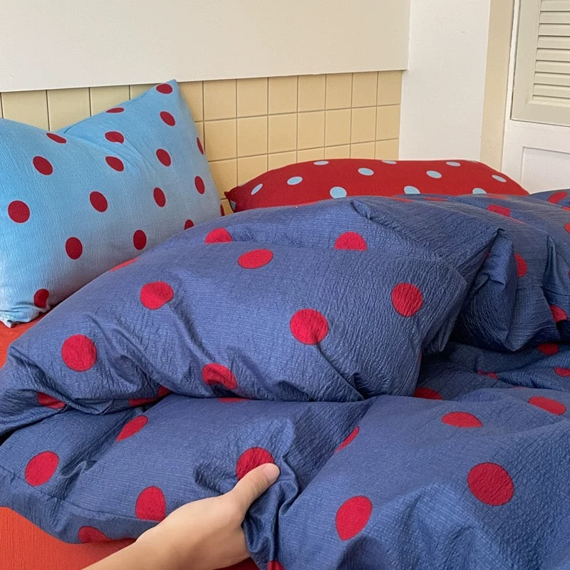 Navy blue bedding with red polka dots creating bold preppy bedroom aesthetic vibe
