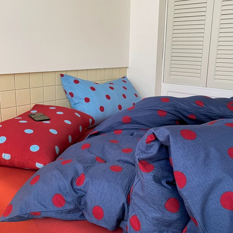 Navy blue polka dot bedding set with red dots styled in classic preppy dorm room