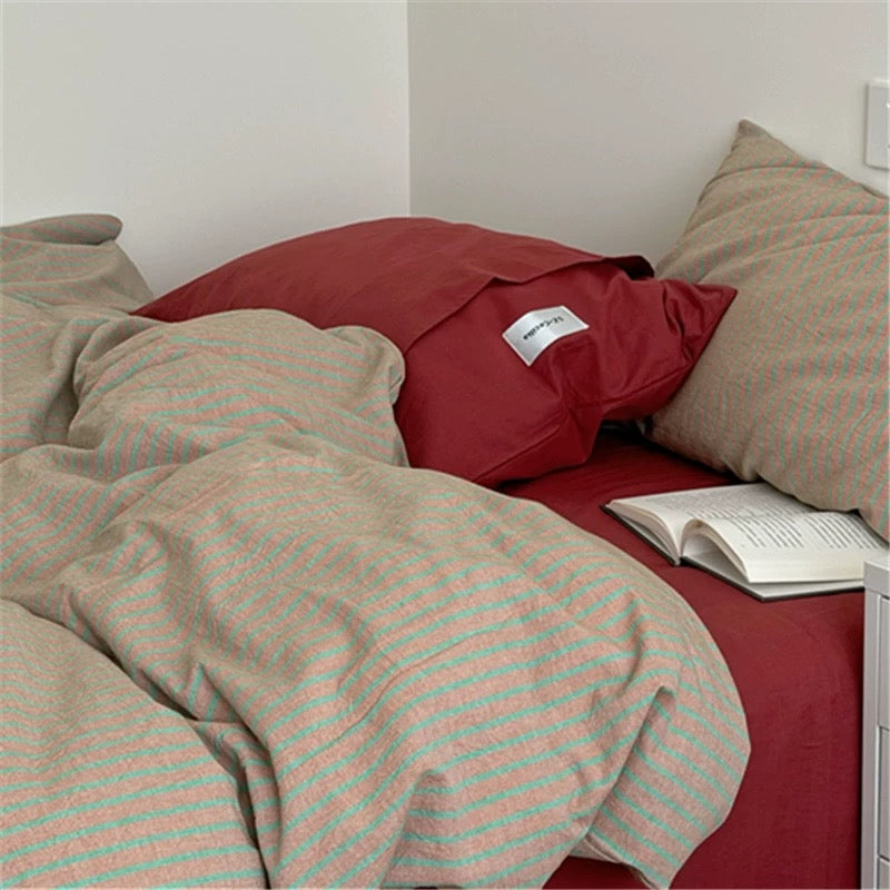 Bed with red and beige bedding, a red pillow, and an open book.