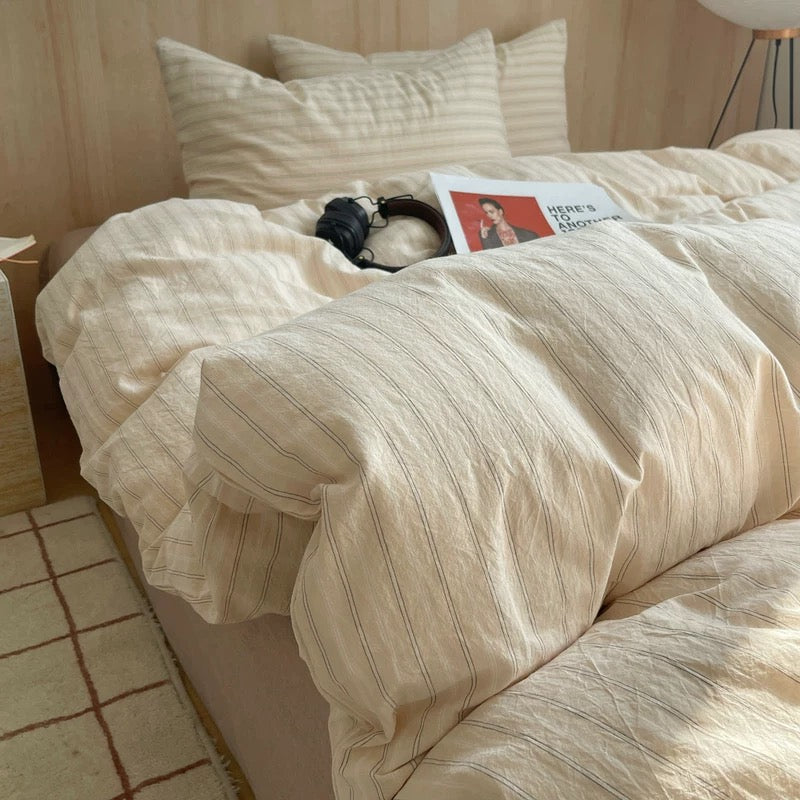 Beige striped bedding on a bed with a wooden headboard.