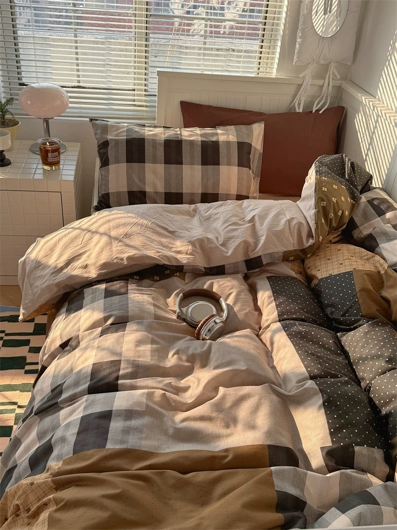 Bedroom with checkered bedding and pillows, a glass of beer on a nightstand.