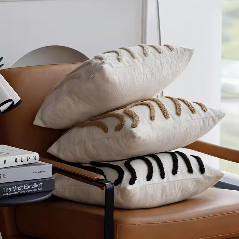 Stack of decorative pillows on a brown leather chair with books in the background