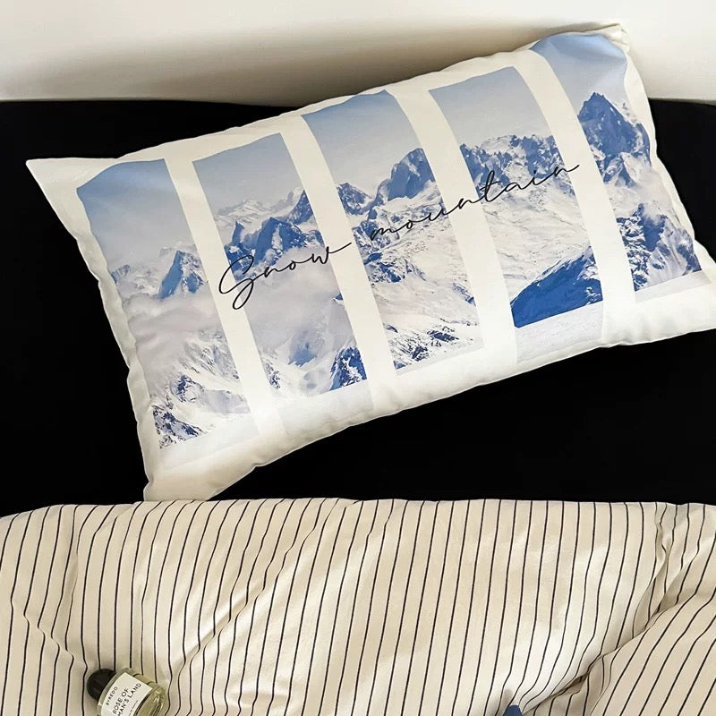 Pillow with mountain design and text on a bed