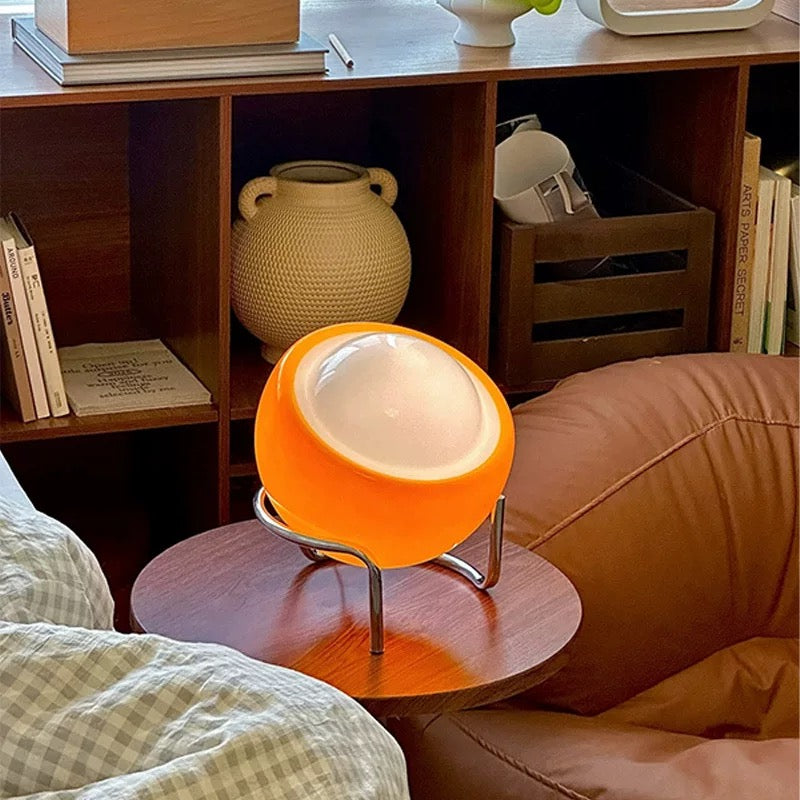 Orange spherical lamp on a wooden side table in a cozy living room setting.