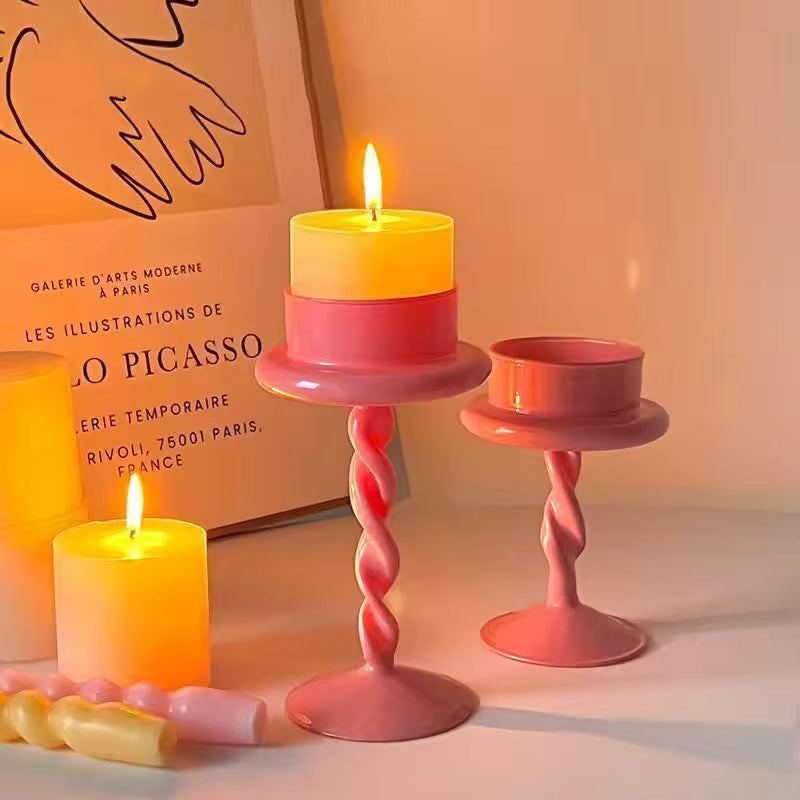 Two lit candles in pink candle holders with a Picasso poster in the background.