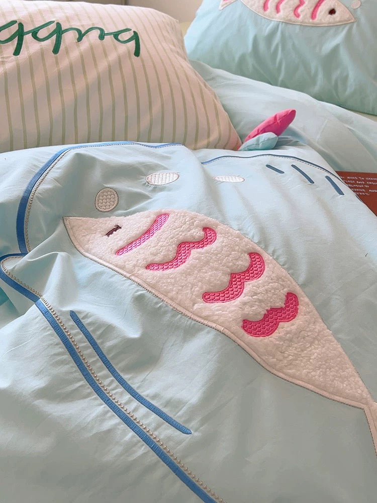 Kawaii blue cotton pillowcases featuring embroidered fish, styled in a light, cozy room.