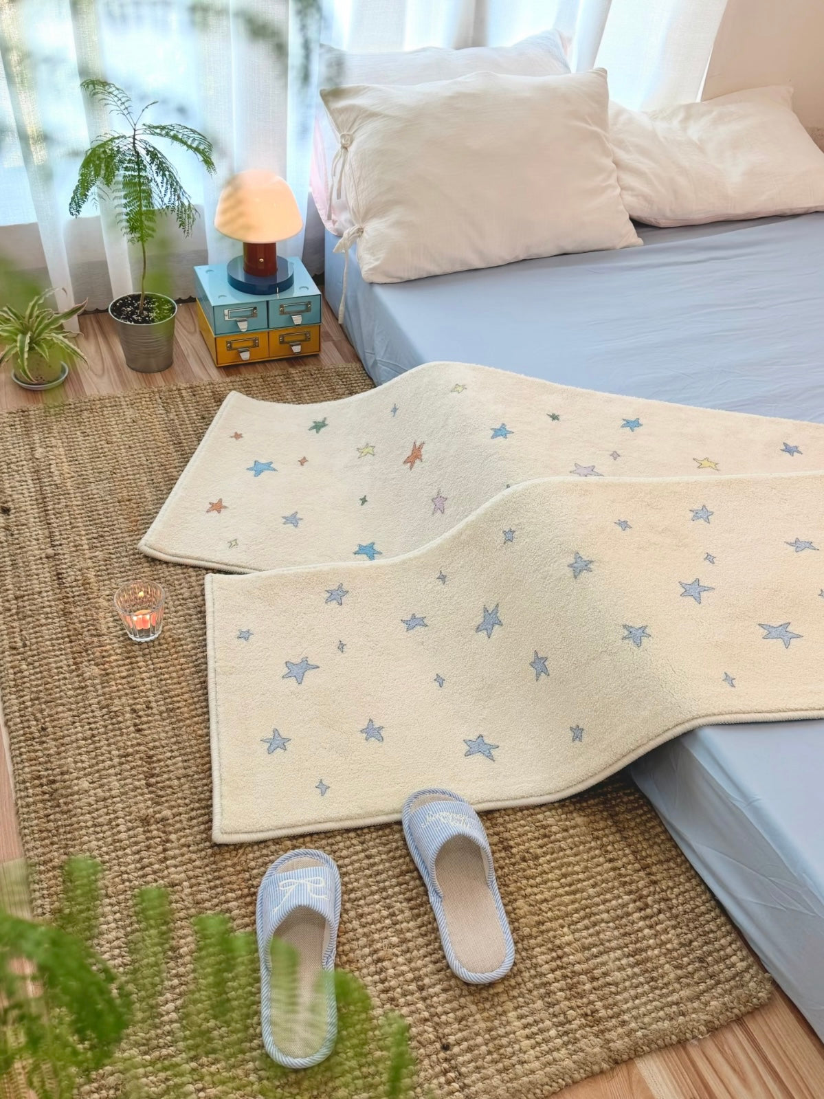 A pastel blue star rug has a raised wave across its cream surface in a wider view of the bedside floor.