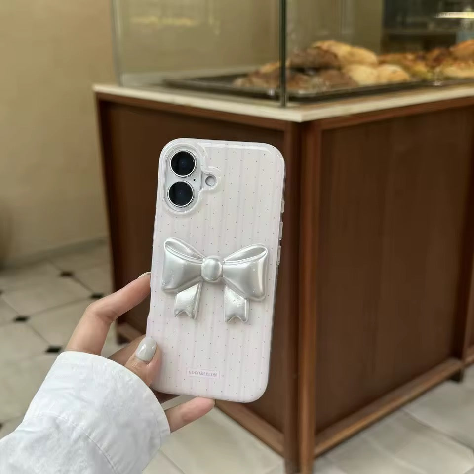 Phone case with bow design held by a person in a bakery setting