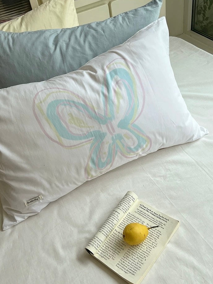Pastel butterfly pillowcase resting against pillows in daylight.