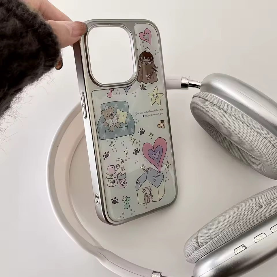 Phone case with cartoon designs held by a hand, placed on a white surface with headphones.