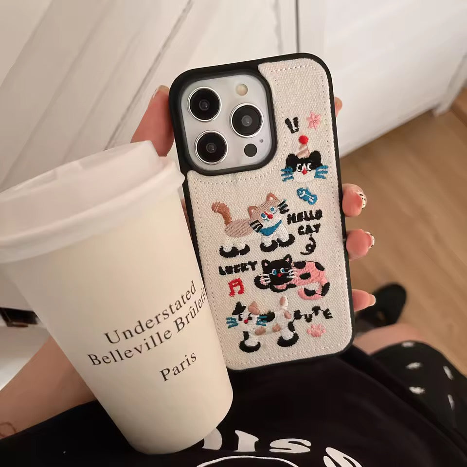 Phone case with cat designs held by a person with a coffee cup.