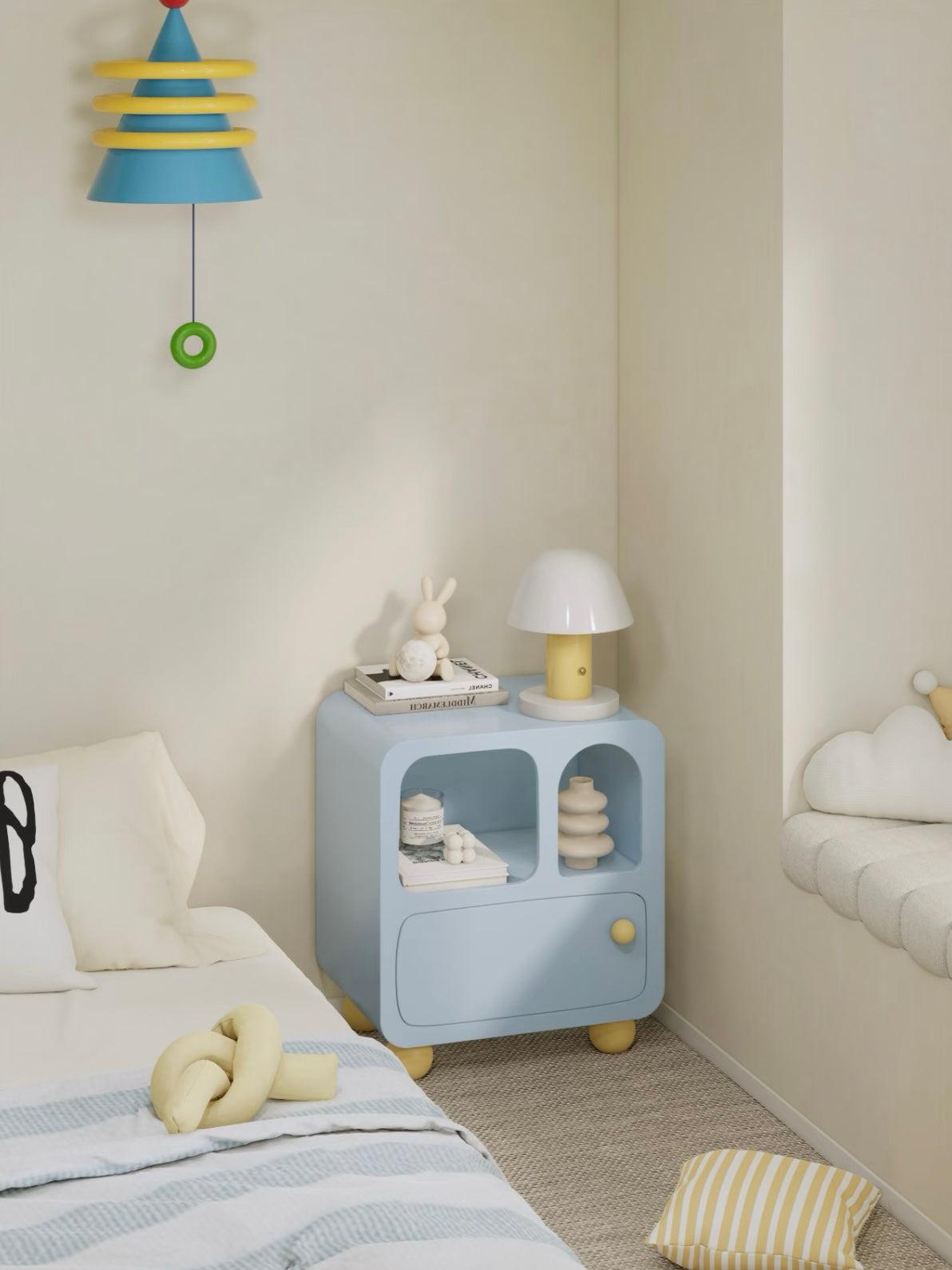 A blue pastel nightstand stands beside a bed in a wide view, with yellow feet and a matching drawer knob.