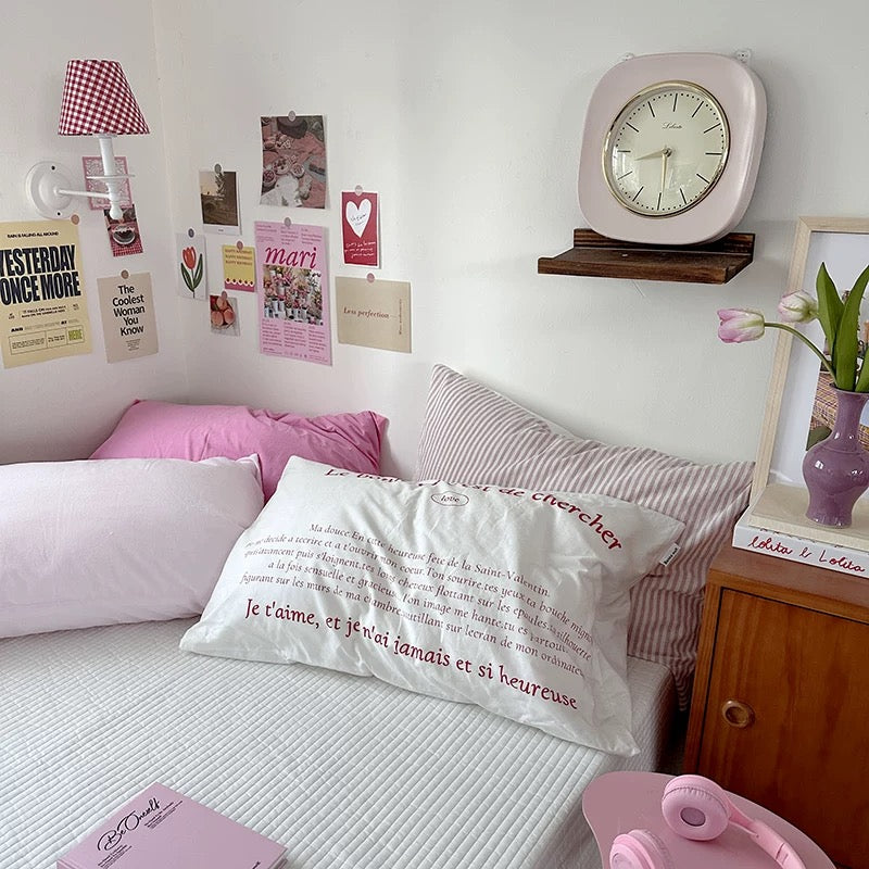 Bedroom with pink pillows, a clock, and decorative items on the wall.