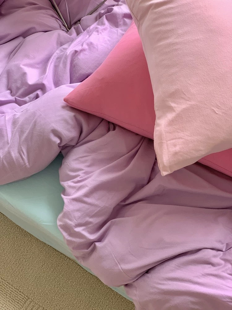 Pink bedding with a light green mattress on a bed.