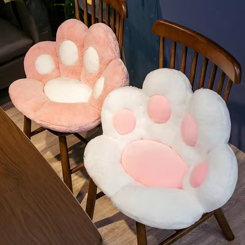 Two paw-shaped cushions on wooden chairs with a neutral background