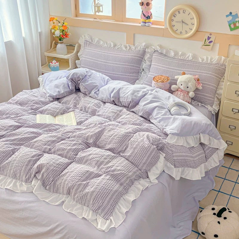 Bed with gray and white checkered comforter and pillows in a bedroom setting.