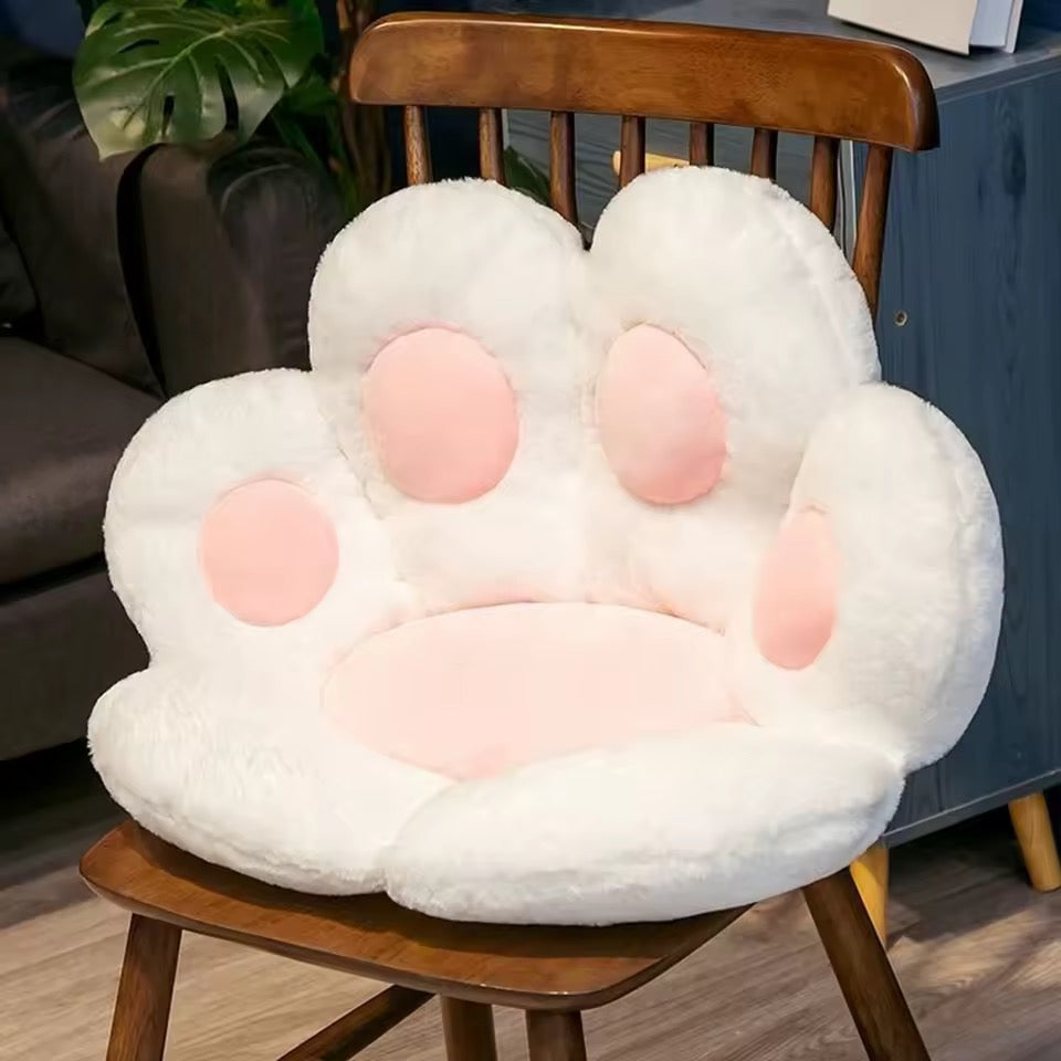 White paw-shaped cushion on a wooden chair with a blurred background