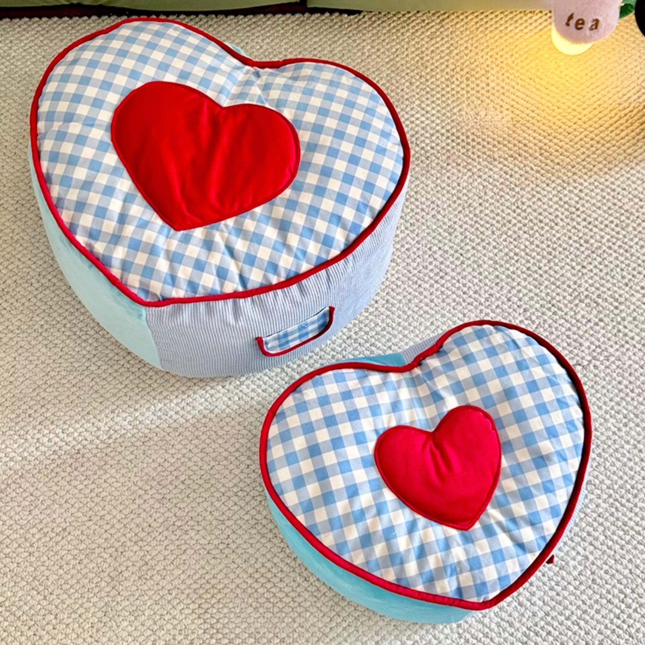 Heart-shaped cushions with blue checkered pattern and red hearts on a textured surface.