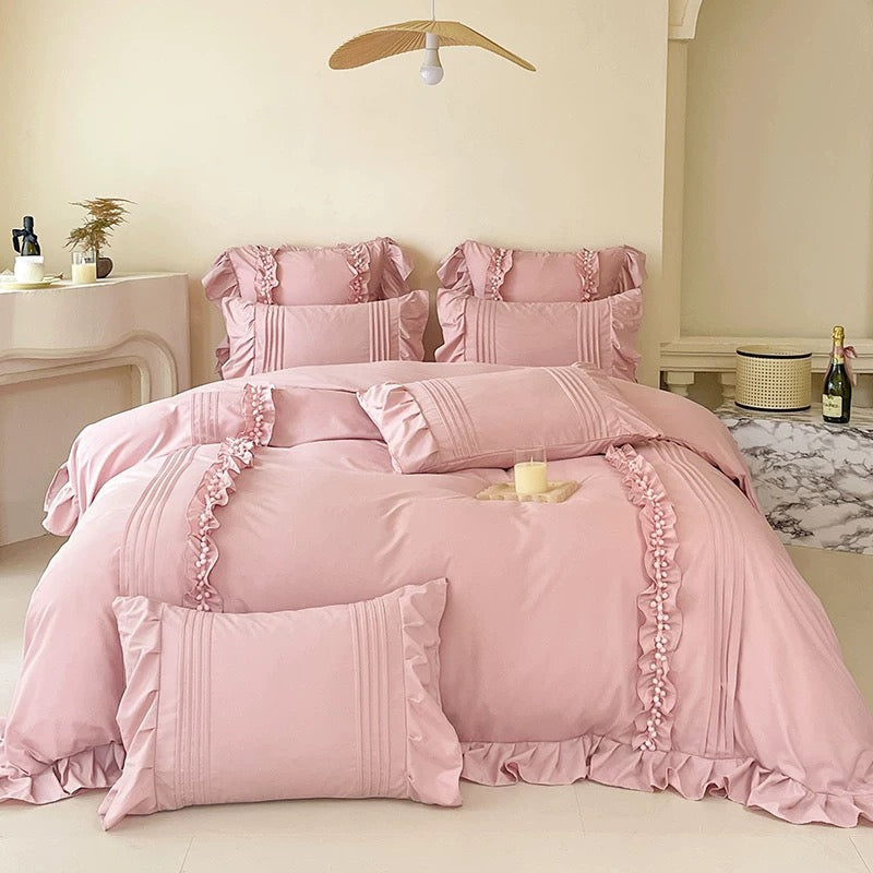 Pink ruffled bedding set on a bed in a bedroom.
