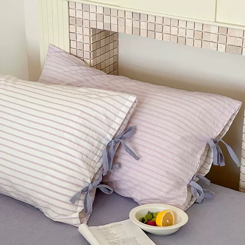 Pastel pink striped cotton pillow cover with bow tie closure, cozy room aesthetic.
