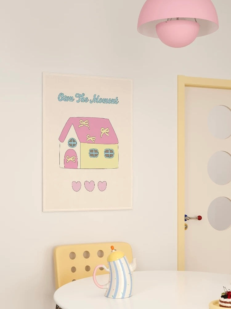 A pastel tapestry with a pink roof is shown beside a pale door, with a striped teapot on the table.