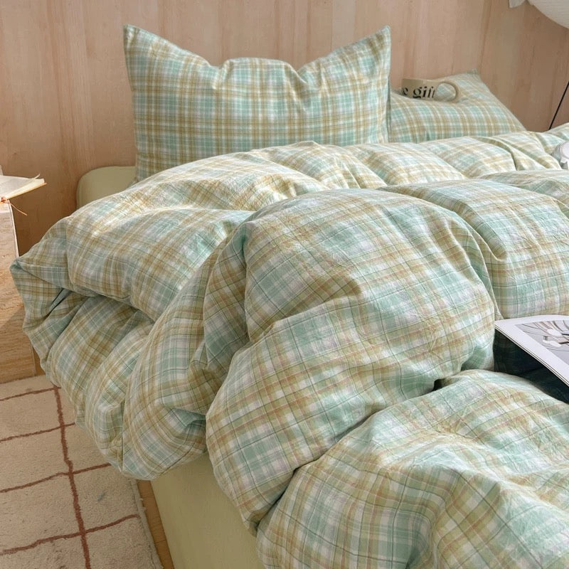 Plaid bedding set on a bed with pillows in a bedroom setting.