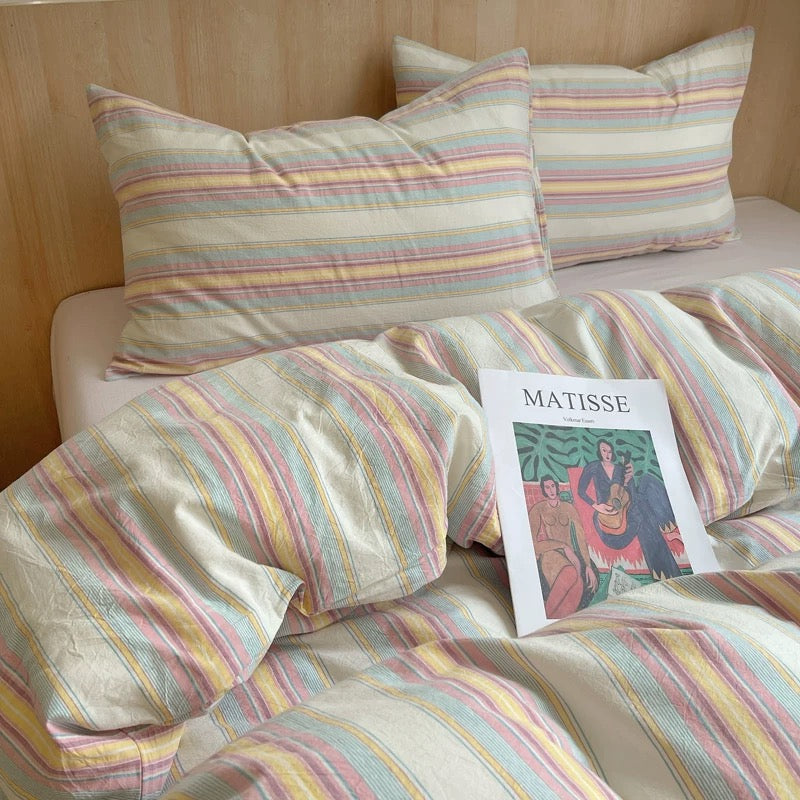 Striped bedding with a book titled 'Matisse' on a bed.
