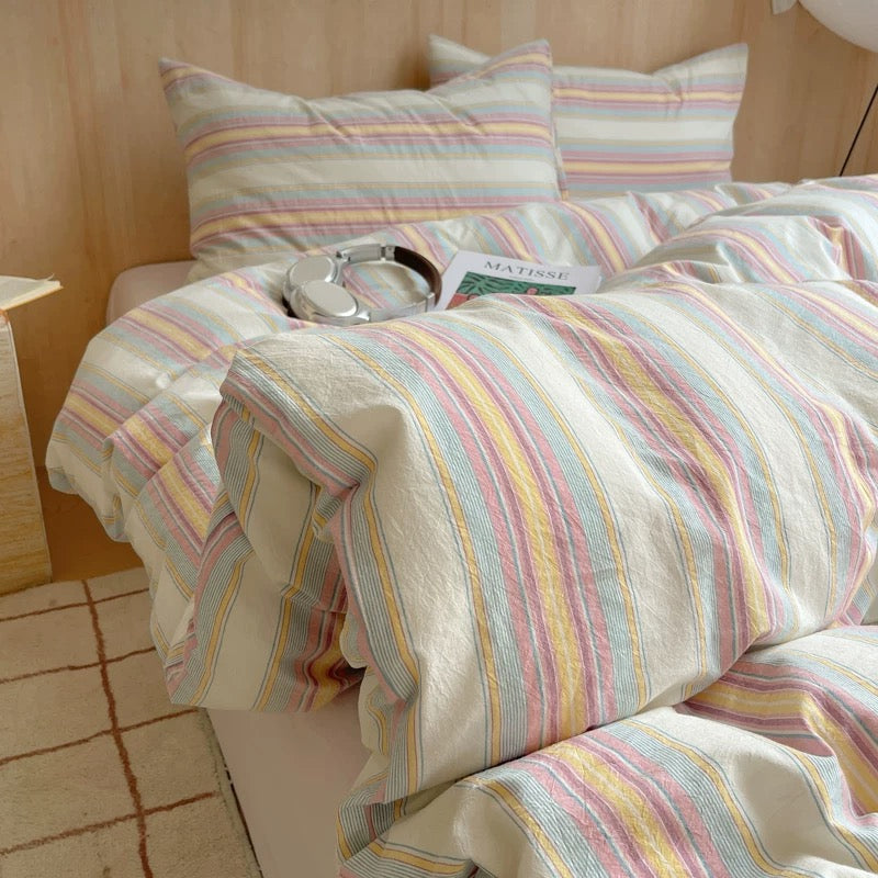 Striped bedding set on a bed with a wooden headboard.