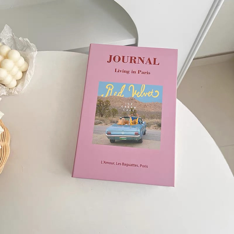 Pink journal with a car and palm tree design on a white surface