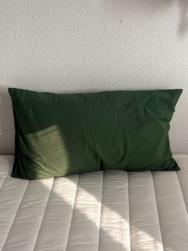 A pine green cotton pillowcase in a solid color with a simple rectangular shape.