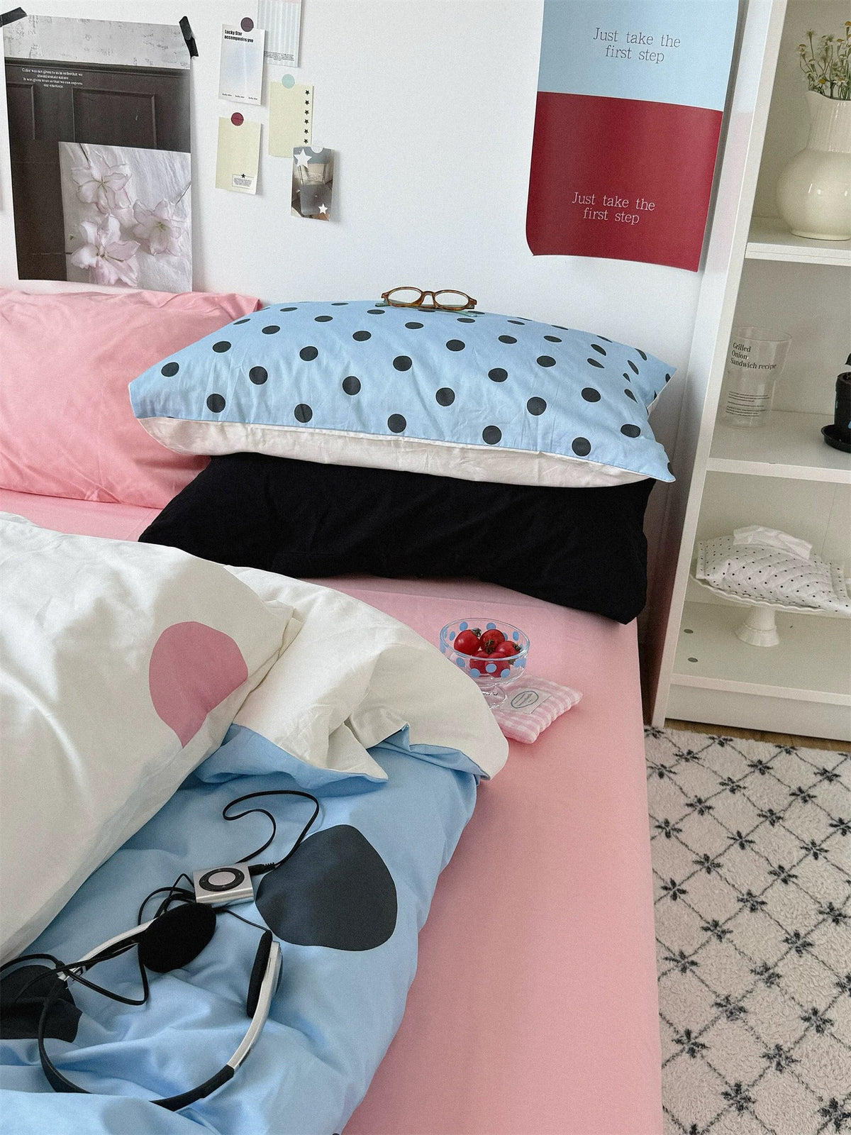 A side view of the pink and blue bedding set shows a small dotted blue pillow resting on a black pillow.