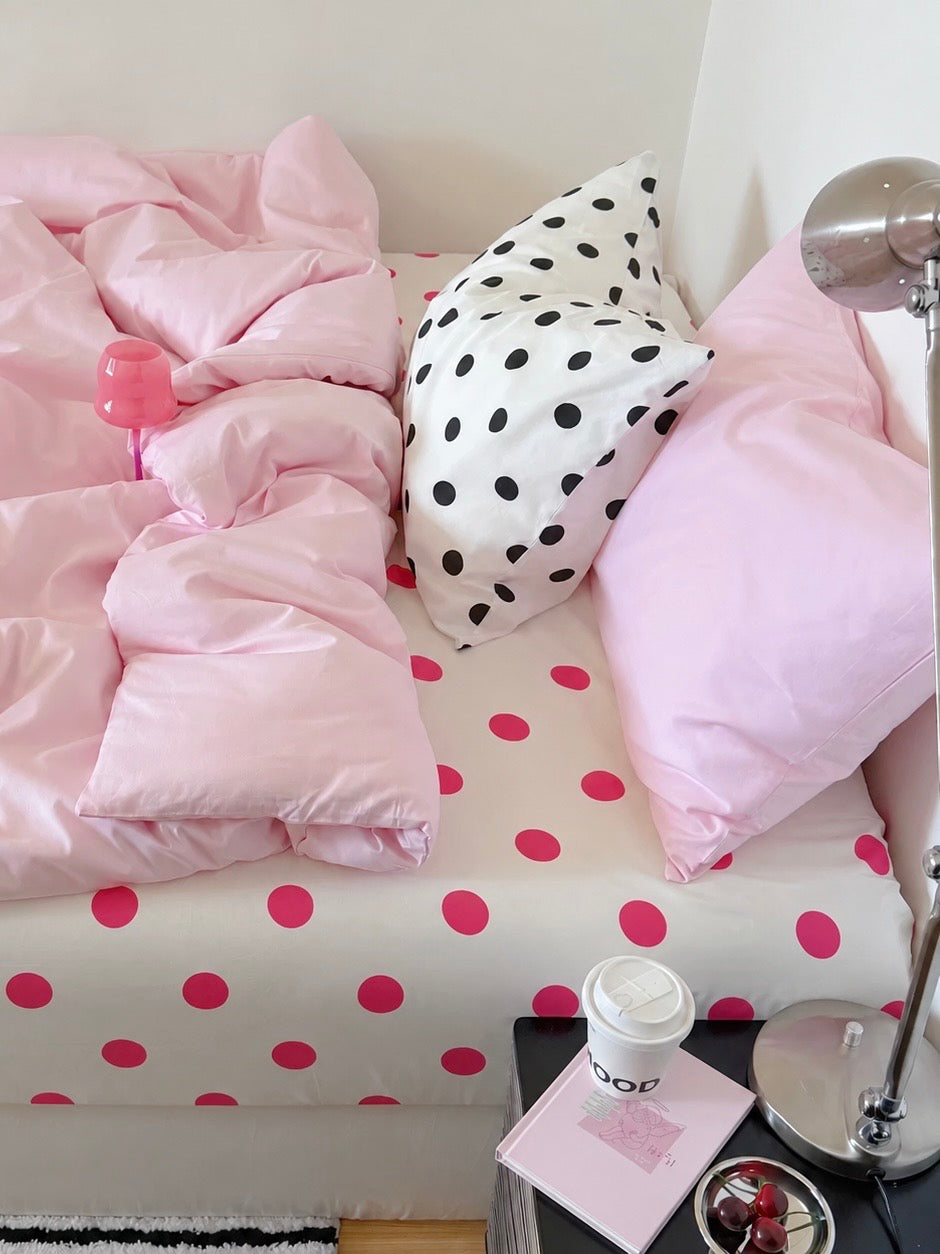 A plain pink duvet cover and pink pillowcase paired with black dots on a white pillowcase.