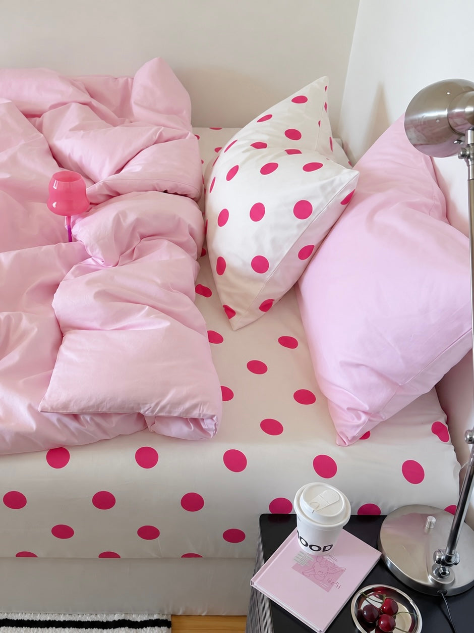 Pink polka dot bedding with a plain pink pillowcase beside a fuchsia dot pillowcase and matching dotted sheet.