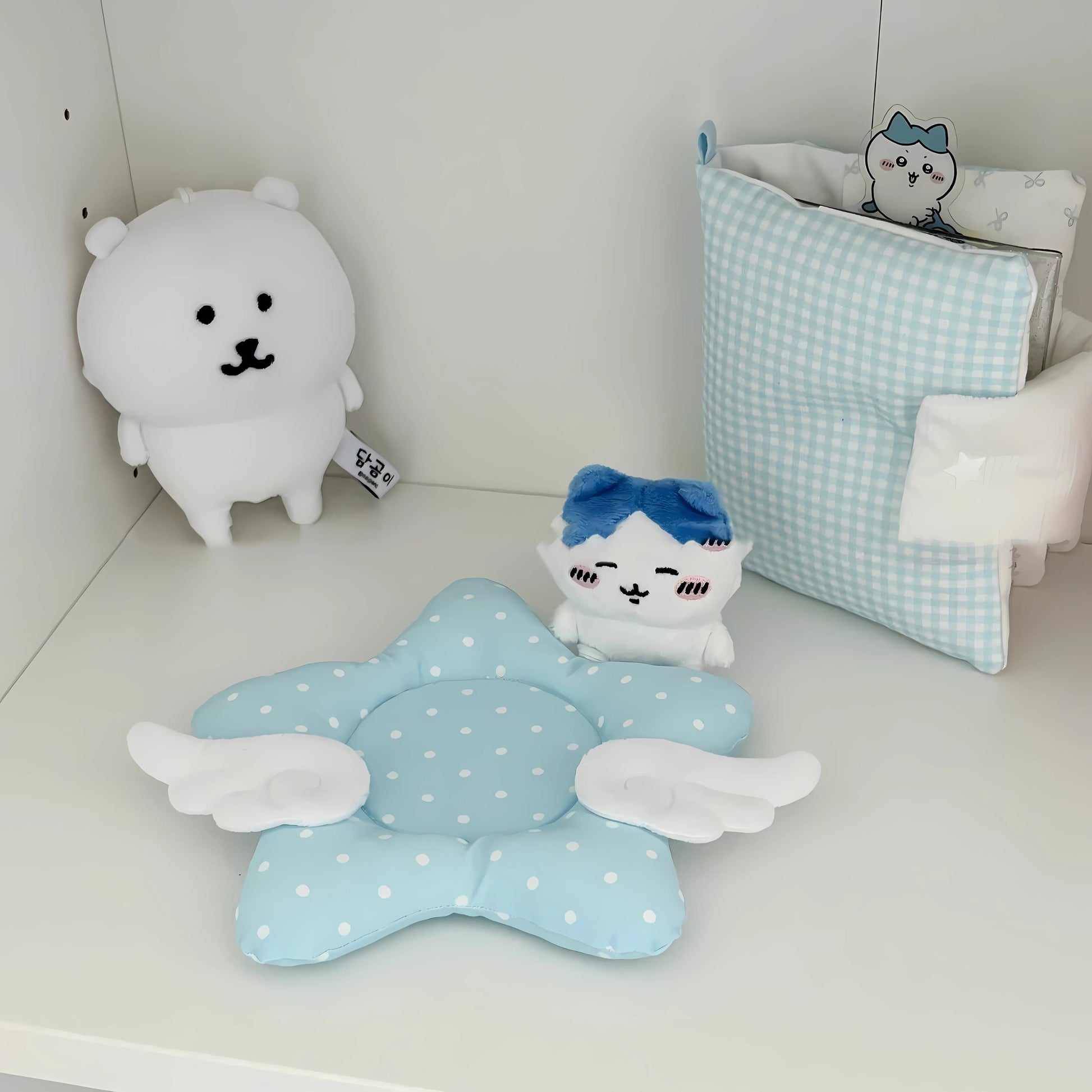 Blue kawaii star coaster with wings, styled on a white desk with plush toys.