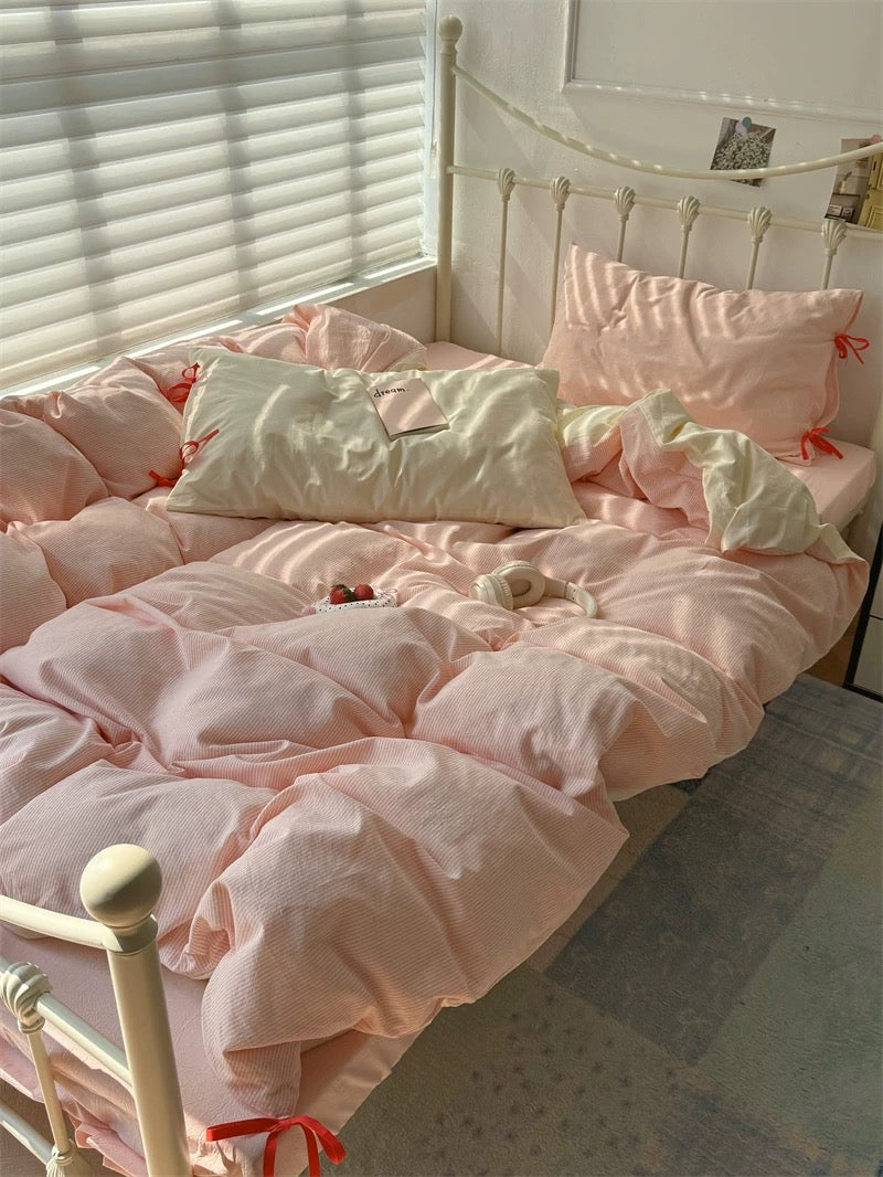 Pink bedroom with a bed covered in pink bedding and pillows.