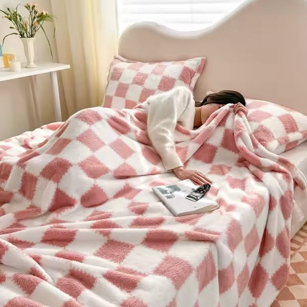 Person lying on a bed covered with a pink and white checkered blanket in a cozy bedroom.